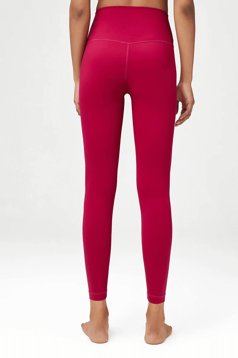 Back view of a woman wearing stylish red high-waist yoga leggings, showcasing the elastic fit and full-length design for active wear.